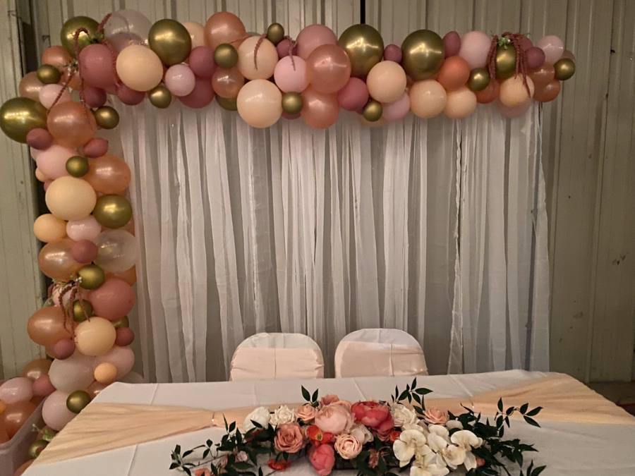 Balloon garland in pink, white, and gold behind the guest of honor table