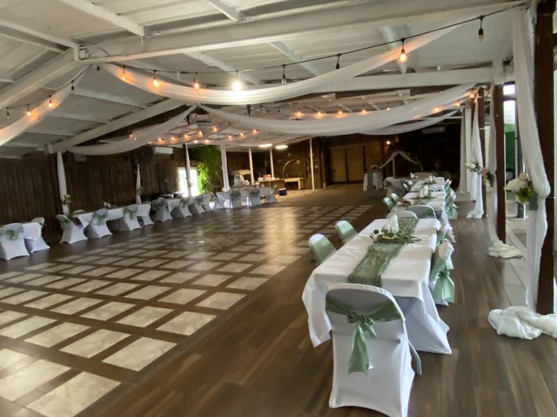 Party hall set with long tables, white linens, and draped fabric across the ceiling
