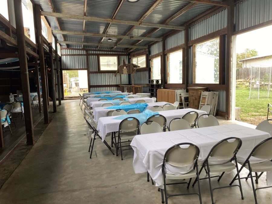 Long tables with white covers beside the open windows of the hall